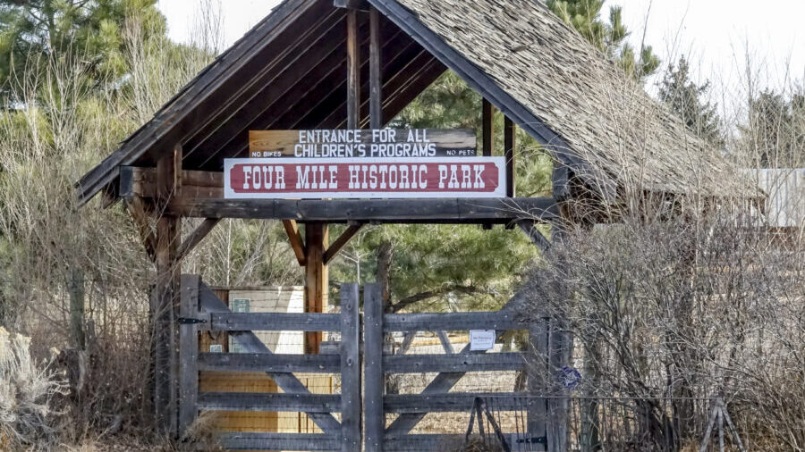 Wooden entrance to Four Mile Historic Park, sign reads "Entrance for All Children's Programs, No Bikes, No Pets"
