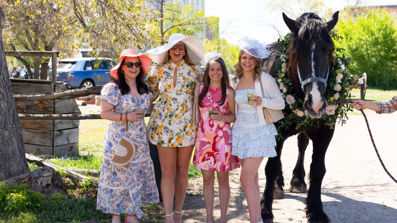 Women in floral dresses and hats smiling with decorated horse
