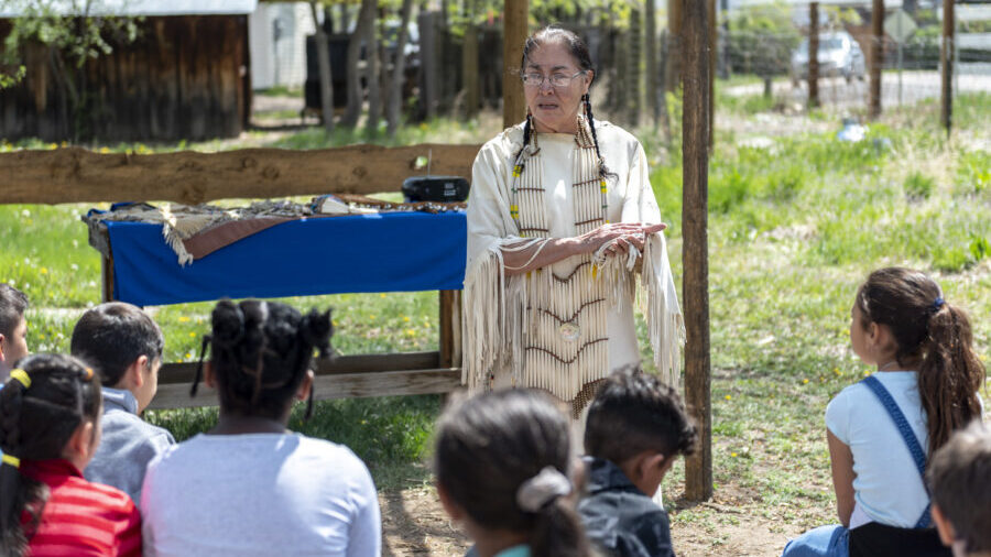 Woman in traditional attire teaching children outdoors