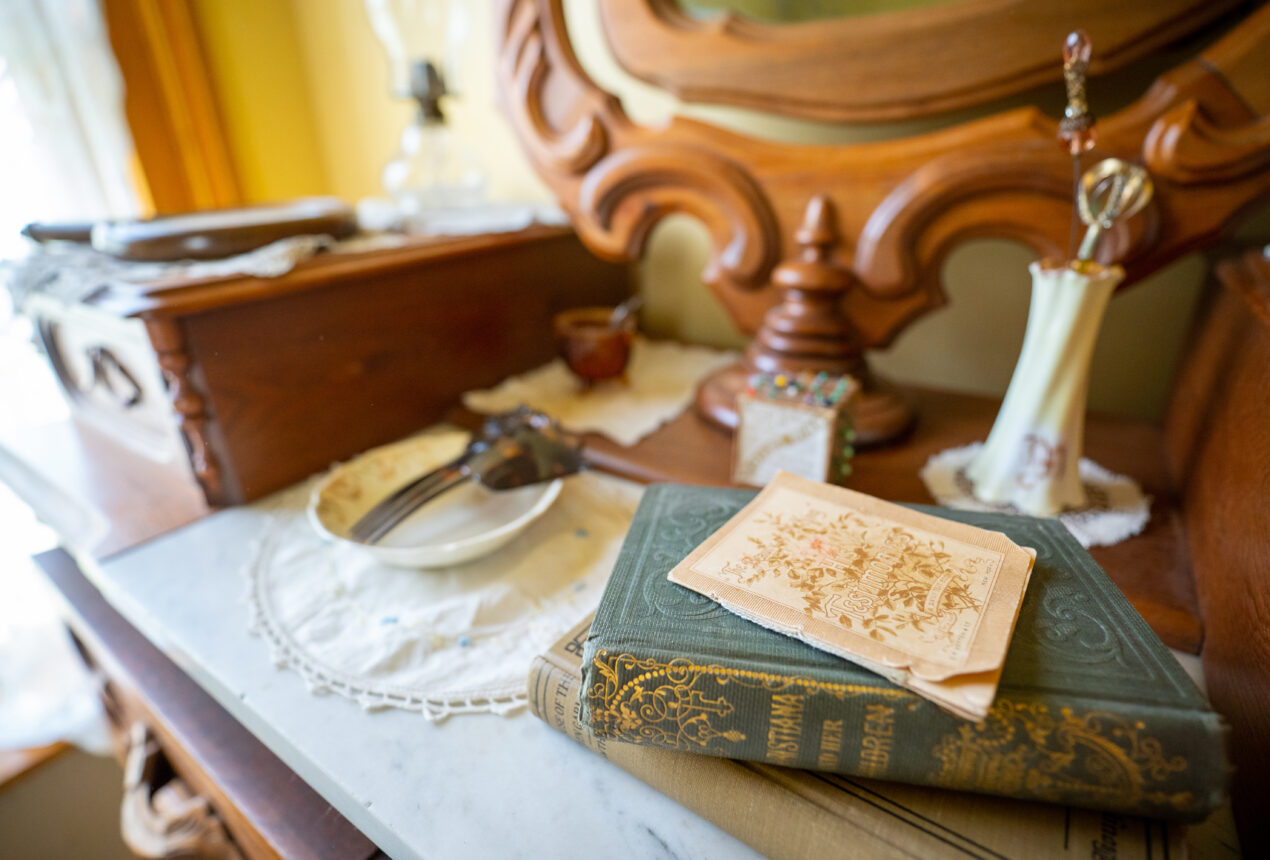 Cómoda antigua con espejo, libros, papeles y objetos decorativos, que transmite un ambiente vintage