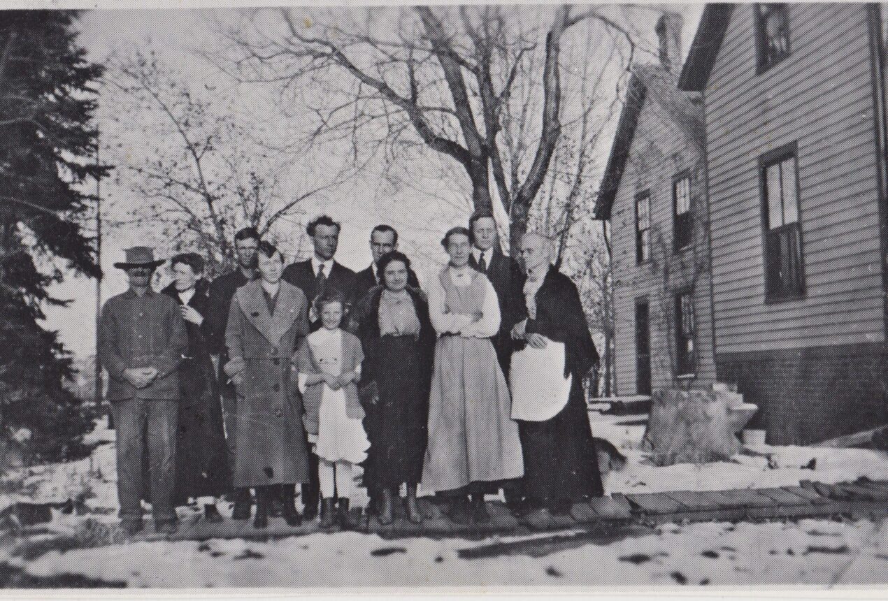 Una familia de principios del siglo XX posando frente a una casa en un paisaje invernal