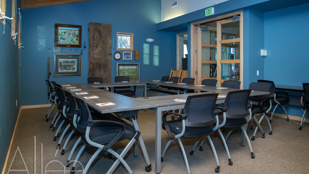 Conference room with U-shaped table, chairs, blue walls, and artwork