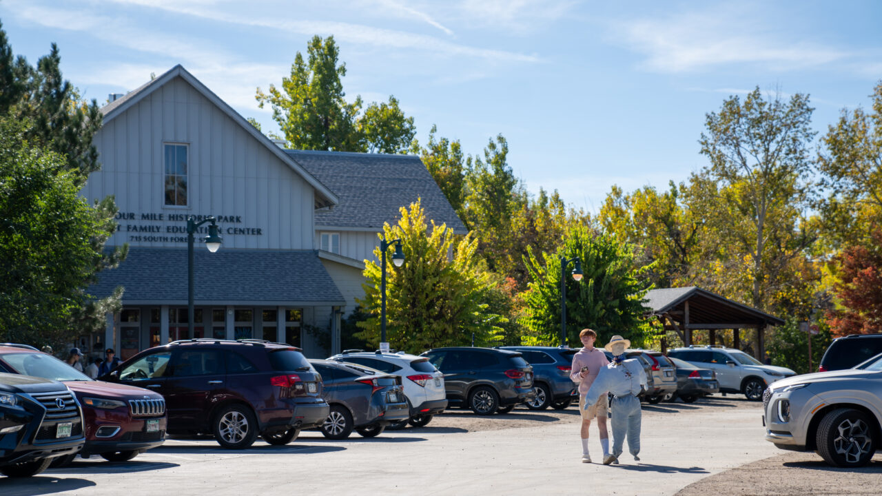 Two people walking through a parking lot towards Four Mile Historic Park Family Education Center