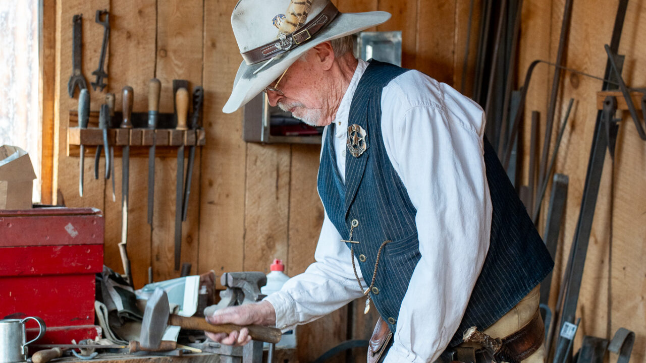 Older man in a workshop, holding a hammer, focused on work